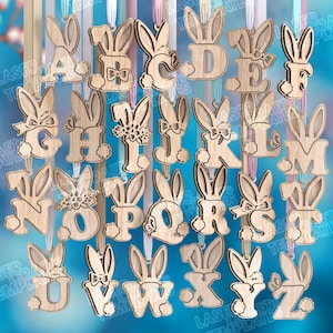 Könnte beinhalten: Holzbuchstaben A bis Z mit Hasenmotiven, verziert mit Schleifen und Blumen. Die Buchstaben hängen an Bändern vor einem blauen Hintergrund.