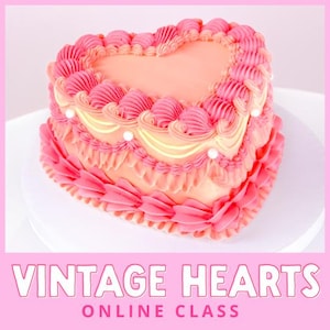 Op de afbeelding: Een hartvormige cake met roze en perzik glazuur, versierd met buttercream details. De cake heeft een vintage design met de tekst "VINTAGE HEARTS ONLINE CLASS" in een roze banner.