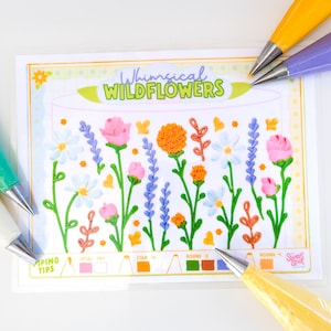 May include: A clear plastic sheet with a floral design, titled "Whimsical Wildflowers," featuring piped buttercream flowers in pink, orange, white, and purple. Piping bags with various colored tips surround the sheet, suggesting cake decorating.