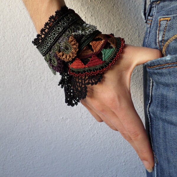 Freeform crochet cuff with taupe brown, maroon, olive green, purple and gray beaded crochet flowers and black lace