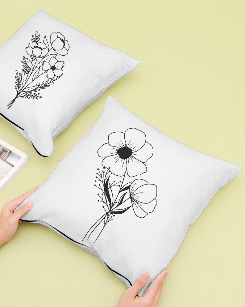 May include: Two white pillowcases with black line drawings of flowers. The pillowcases have a black trim around the edges.