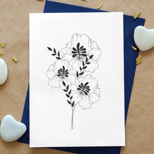May include: A white card with a black line drawing of three flowers with leaves on a blue envelope. The envelope is on a brown surface with gold confetti.