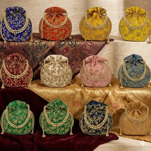 May include: A selection of embroidered drawstring bags in shades of blue, red, yellow, and green. Each bag showcases detailed floral designs and is embellished with a pearl-style beaded handle. The bags are displayed on a patterned fabric surface.