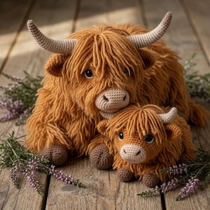 May include: A large and a small Highland cow stuffed animal made of textured ginger-brown yarn. Both figures feature long shaggy fur, light beige crocheted muzzles, dark eyes, and curved horns. The pair is positioned together on a wooden surface.