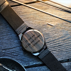 May include: A wooden wristwatch with a brown leather band. The watch face is engraved with the message "I'll love you till the end of time - Christina".