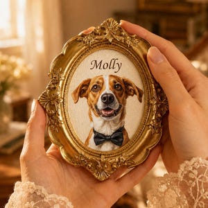 Könnte beinhalten: Ein ovaler, verzierter goldfarbener Bilderrahmen mit dem Porträt eines braun-weißen Hundes, der eine schwarze Fliege trägt. Der Name Molly ist in schwarzer Schreibschrift über dem Kopf des Hundes auf dem cremefarbenen Hintergrund gedruckt.