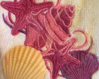 Débarbouillette avec motif coquillages roses brodés et savon assorti.