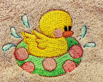 Serviette d'invité rose avec canard brodé dans un anneau gonflable