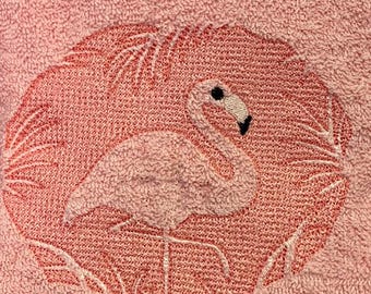 Motif flamant rose brodé sur une serviette à main rose.
