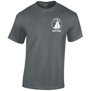 May include: A dark grey t-shirt with a white graphic. The graphic includes a sailboat, birds, and the text "PRESTIGE WORLDWIDE PRESENTS BOATS & HOES" in a circular design. The t-shirt is made of a soft material.