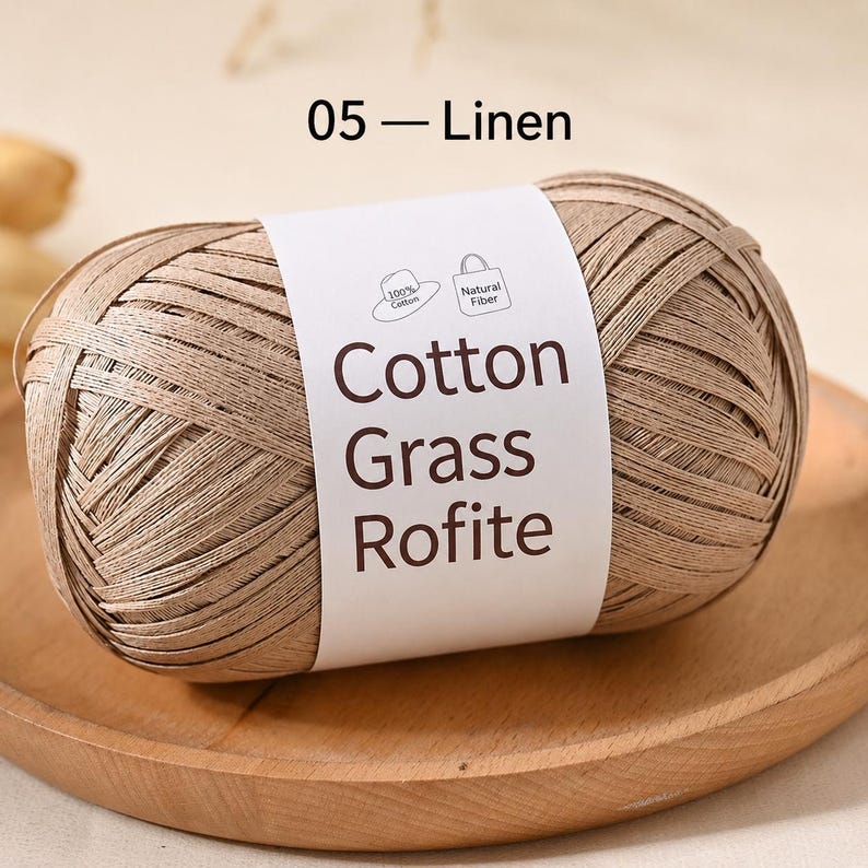 May include: A ball of light brown, flat, ribbon-like yarn labelled 05 - Linen. The white paper band features the text Cotton Grass Rofite, along with small icons of a hat and a tote bag, indicating 100% cotton and natural fibre content.