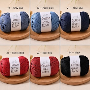 May include: Six balls of Cotton Grass Rofite yarn in colours grey blue, azure blue, navy blue, Chinese red, rose red, and black. Each ball features a white paper label with the text Cotton Grass Rofite and icons of a hat and a bag.