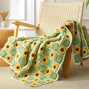 May include: A green and yellow crocheted throw blanket with a sunflower pattern. The blanket is draped over a wooden chair.