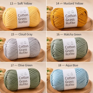 May include: Six skeins of Cotton Grass Rofite yarn in soft yellow, mustard yellow, cloud gray, matcha green, olive green, and aqua blue. Each oval-shaped ball features a white paper label with the text Cotton Grass Rofite and icons of a hat and bag.