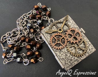 Può includere: Un ciondolo a medaglione rettangolare color argento con un motivo floreale in rilievo e tre ingranaggi metallici con lancette d'orologio fissate sul davanti. Il ciondolo pende da una catena argentata intervallata da perline marrone scuro e metalliche.