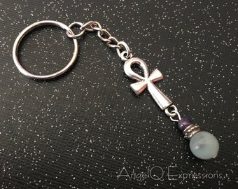 Può includere: Portachiavi d'argento con un ciondolo ankh e una perla blu chiaro e viola.