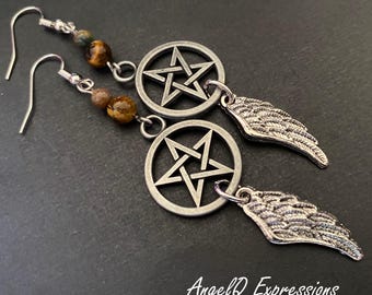 Può includere: Un paio di orecchini pendenti con ciondoli a pentagramma in metallo color argento e ciondoli ad ala d'angelo testurizzati. Ogni orecchino include due perline occhio di tigre marroni e dorate su un gancio argentato. Il testo AngelQ Expressions è visibile.