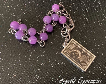 Può includere: Un braccialetto a catena d'argento con perline color lavanda e un ciondolo con una carta dei tarocchi con il testo "The Moon".