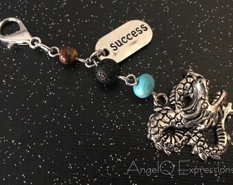 Può includere: Un braccialetto con ciondolo in argento con un ciondolo a forma di drago, una perla turchese, una perla di lava nera, una perla di occhio di tigre e un'etichetta in argento che dice "successo".