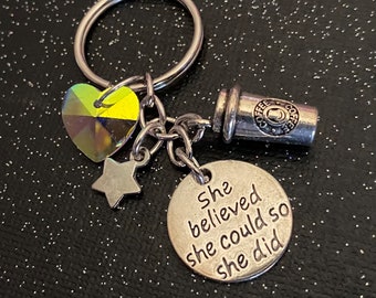 Può includere: Portachiavi d'argento con un ciondolo che dice "She believed she could so she did". Il portachiavi ha anche un ciondolo a forma di tazza da caffè, un ciondolo a forma di stella e un ciondolo a forma di cuore.
