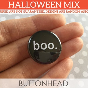 Puede incluir: Un bot&oacute;n redondo de color negro con el texto en min&uacute;sculas de color blanco 'boo.' impreso en el centro. El bot&oacute;n tiene un acabado brillante y forma parte de un surtido de Halloween. El texto es claro y est&aacute; centrado en la superficie circular.