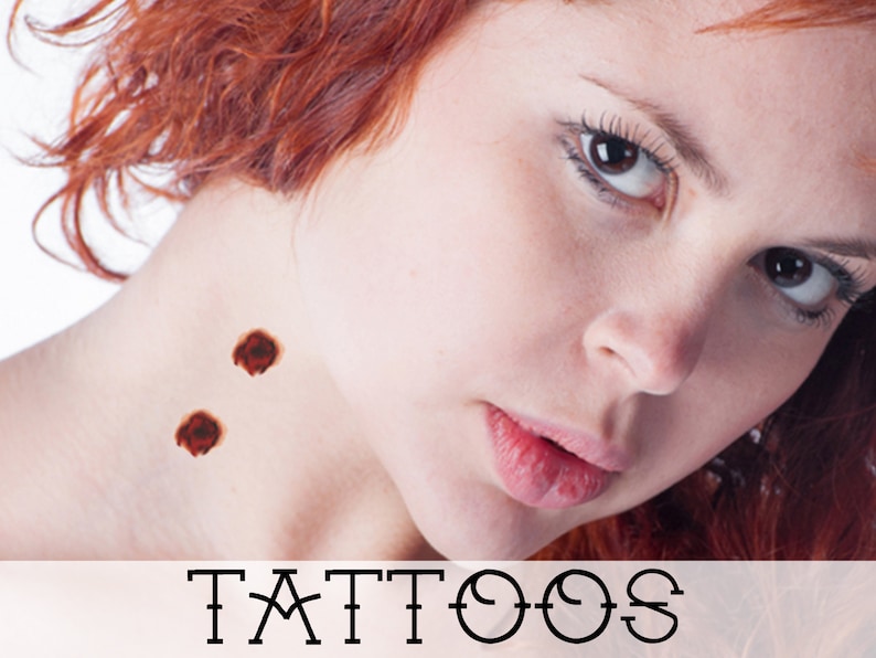 May include: A temporary tattoo featuring two dark red, circular puncture marks resembling vampire bite wounds, positioned on the side of a neck. The word TATTOOS is printed in a black, stylized serif font at the bottom of the image.