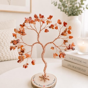 May include: A decorative wire tree sculpture featuring numerous small, polished orange-red gemstone chips as leaves. The tree has a twisted copper-coloured wire trunk and branches, mounted on a circular wooden base with the text "17 Years, David and Shawn, I Will Love You Forever" and two small red heart icons engraved on the side.
