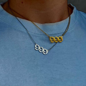 以下が含まれることがあります： 999と刻まれたネックレスが2本。上のネックレスは金色で、下のネックレスは銀色です。