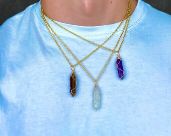 May include: Three gold chains with different colored crystal pendants. The pendants are wrapped in gold wire and are shaped like long, thin points. The crystals are purple, brown, and light blue.