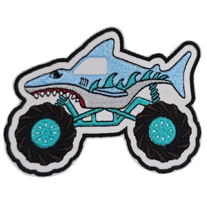May include: An embroidered patch of a blue and teal monster truck shaped like a shark. The truck has large black tires with teal rims. The shark has white teeth and a gray belly.