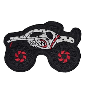 May include: Black and white monster truck patch with red wheels. The truck has a dalmatian-like pattern and a snarling face.