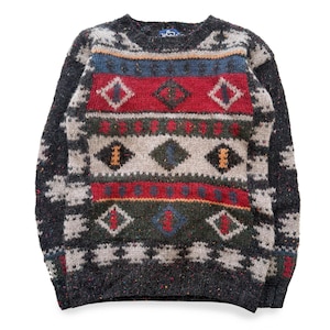 May include: A dark grey crew neck sweater featuring a vibrant geometric pattern. The design incorporates red, blue, green, and cream diamond and stripe motifs. The sweater is constructed from a thick knit fabric.
