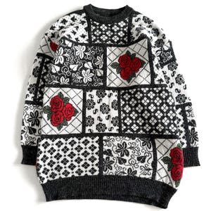 May include: A grey sweater with a patchwork design featuring black and white geometric patterns and red roses.