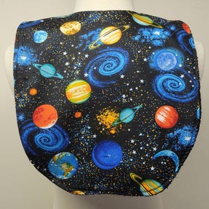 May include: A black fabric with a space-themed print featuring planets, stars, and galaxies in shades of blue, orange, yellow, and white.