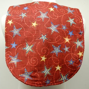 May include: Red fabric bib with a pattern of blue, yellow, and white stars on a red background. The stars are outlined in white and have a swirl pattern.