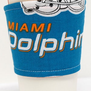 May include: A blue and orange fabric coffee cup sleeve with the text "MIAMI Dolphins" in white and orange lettering.