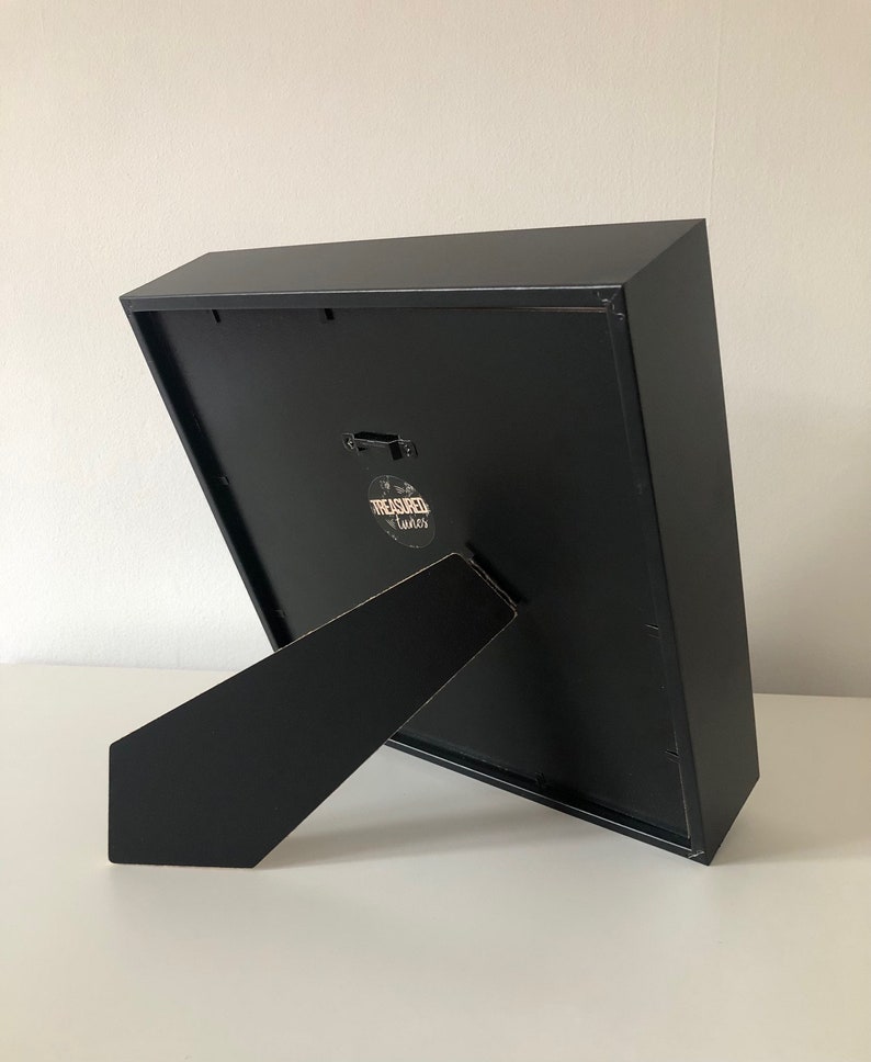 May include: Black picture frame with a black easel stand. The frame has a small sticker on the back that says "Treasured Times".