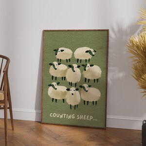 Könnte beinhalten: Ein gerahmtes, rechteckiges Wandbild mit einem texturierten olivgrünen Hintergrund und acht cremefarbenen Schafen mit dunkelgrünen Gesichtern und Beinen. Der Text "COUNTING SHEEP..." ist in hellem Cremeton am unteren Rand aufgedruckt.
