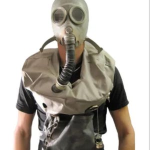 May include: A grey gas mask with circular eye pieces and a corrugated hose. The mask is worn with a matching grey protective vest and a black shirt. The mask is a vintage style.