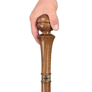 May include: A wooden walking stick with a brown, rounded handle and a decorative brass band. The stick is made of dark wood and has a smooth finish.
