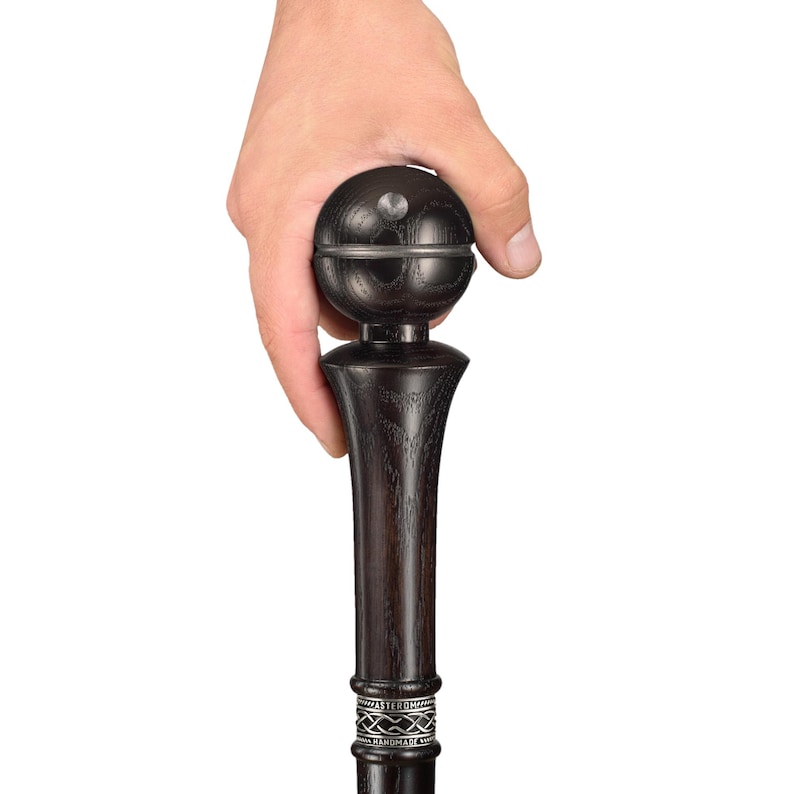 May include: A black wooden walking stick with a round, dark wood knob on top. The knob has a silver band around it. The stick has a silver band with an inscription around the shaft.