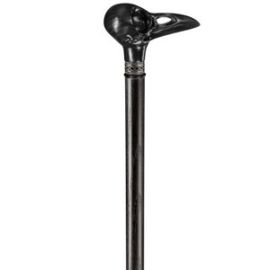 May include: A black walking stick with a carved raven skull handle. The handle has a silver band with a decorative design.