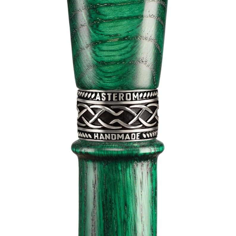 May include: Close-up of a green wooden walking stick with a silver band that reads "Asterom Handmade".