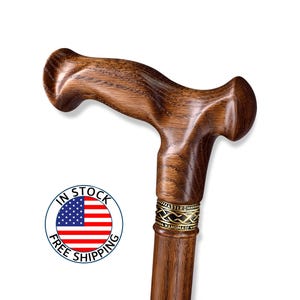 K&ouml;nnte beinhalten: Handgefertigter Gehstock aus Holz mit gebogenem Griff und dunkelbraunem Finish. Der Stock hat ein dekoratives goldfarbenes Band in der N&auml;he der Oberseite und den Text "MASTER ROMA HANDMADE". Ein Aufkleber "IN STOCK FREE SHIPPING" ist sichtbar.