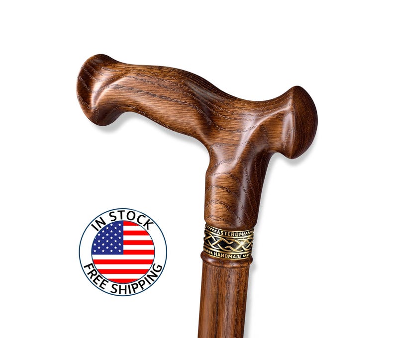 K&ouml;nnte beinhalten: Handgefertigter Gehstock aus Holz mit gebogenem Griff und dunkelbraunem Finish. Der Stock hat ein dekoratives goldfarbenes Band in der N&auml;he der Oberseite und den Text "MASTER ROMA HANDMADE". Ein Aufkleber "IN STOCK FREE SHIPPING" ist sichtbar.