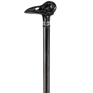 May include: A black walking stick with a carved crow skull handle. The handle has a silver band with a decorative pattern.