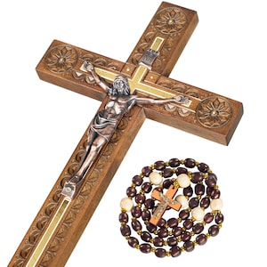 May include: A wooden crucifix with a silver-toned Jesus figure and decorative carvings. A rosary with brown and cream-colored beads and a small wooden cross is also present. The cross is approximately 18 inches long.
