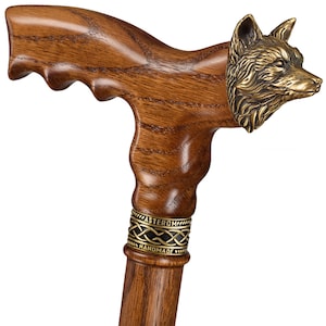 May include: A wooden walking stick with a fox head handle. The handle is made of dark wood and has a detailed fox head carved into it. The stick is decorated with a gold band with the words "Masterpiece Handmade" engraved on it.
