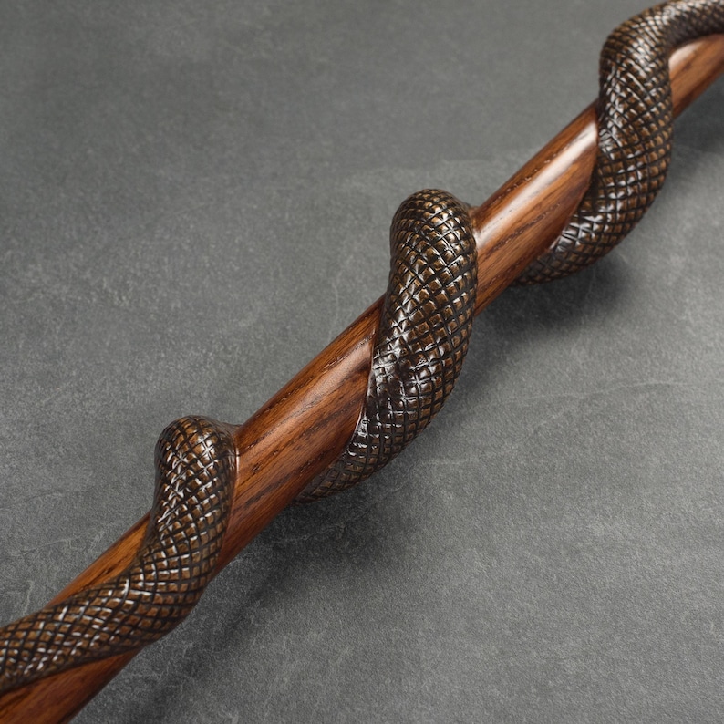 May include: A wooden walking stick with a carved snake design. The snake is wrapped around the stick and has a detailed, textured pattern.