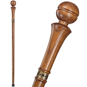 May include: A wooden walking stick with a rounded knob handle and a decorative metal band. The stick is brown and has a natural wood finish.